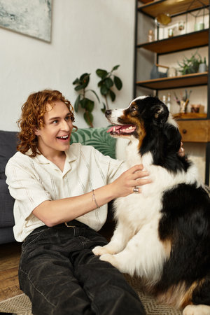 A young man shares joyful time with his furry friend in a warm, inviting living space.のeditorial素材