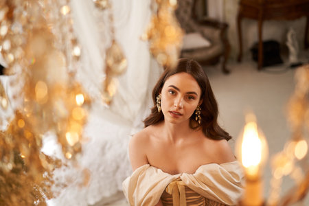 A young woman with graceful elegance poses in a vintage dress, surrounded by luxurious decor.の写真素材