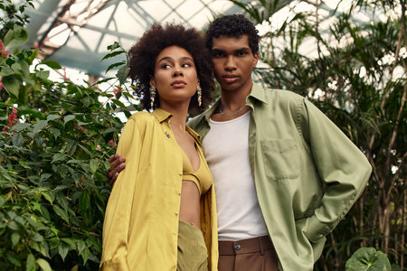 Young couple shares a tender moment among flourishing plants in a beautiful greenhouse.の写真素材