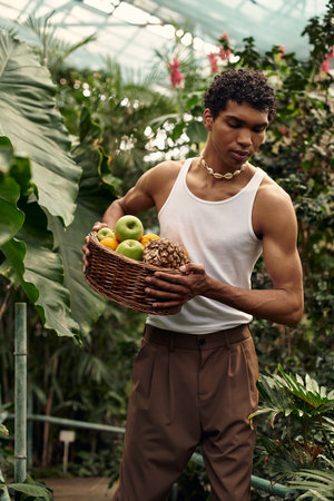 A handsome man enjoys a tender moment amid vibrant plants and fruits in a greenhouse.の写真素材