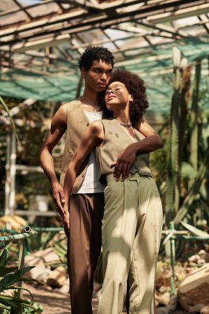 In a serene greenhouse, a loving couple embraces, surrounded by lush plants and natural beauty.の写真素材