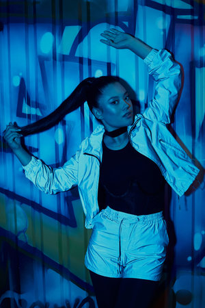 A stylish woman strikes a confident pose before vibrant street art, radiating urban flair.の写真素材