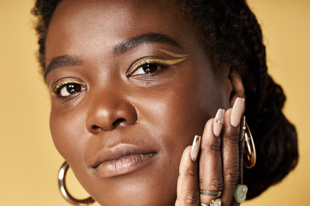 Young African American woman showcases radiant skin and unique makeup in a studio setup.