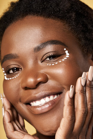 Young woman with flawless skin showcases radiant beauty in a bright studio environment.の写真素材