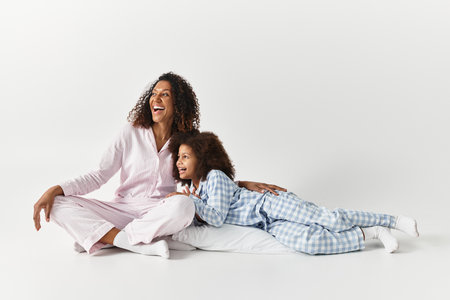An African American mother and her daughter share a joyful moment, dressed in matching pyjamas.の写真素材
