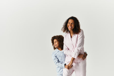 Black mother and daughter in matching PJs smiling in studio, bannerの写真素材