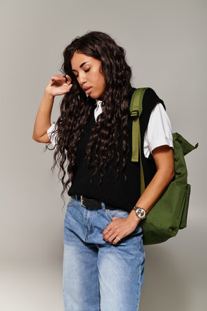 Beautiful student showcases young aesthetics with a relaxed pose and trendy outfit indoors