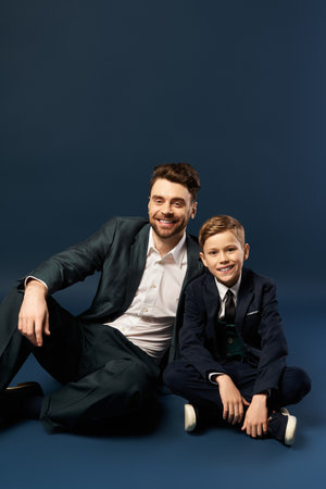 A father and son share smiles while stylishly dressed, capturing a moment of togetherness.
