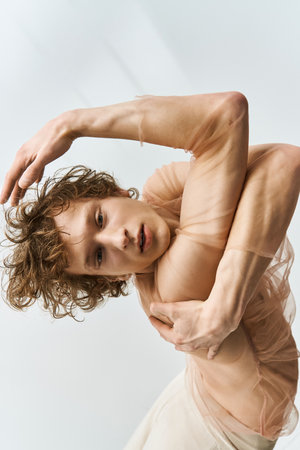 A young man with curly hair showcases his athletic skills while dancing in a minimalist studio.