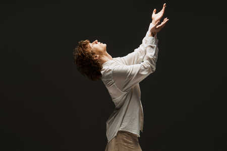 Young curly dancer showcases graceful movements in a studio, embodying emotion and artistry.の写真素材