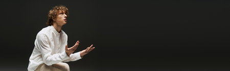 Young curly man dances with passion in a minimalist studio, showcasing athletic grace and artistry,...