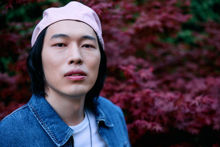 A young asian man showcases his denim fashion in a colorful park, radiating confidence and style.の写真素材