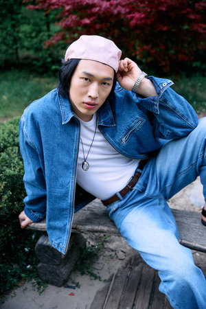 Young man showcases a trendy denim ensemble while enjoying a serene afternoon outdoors.の写真素材