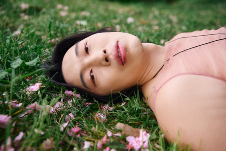 A young Asian man relaxes on the grass, enjoying nature.の写真素材