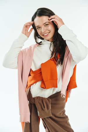 A young woman in fashionable attire smiles while adjusting her stylish outfit in a bright space.