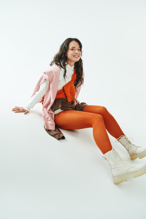A young woman shows her style with bold colors and chic boots while sitting gracefully.