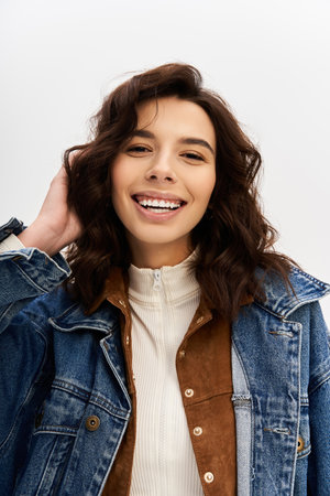 A vibrant young woman confidently models her unique style against a grey studio backdrop.