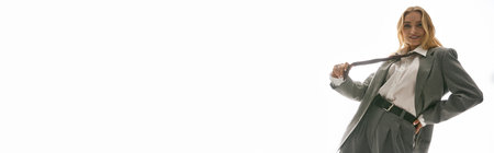 Stylish young woman confidently poses in a chic suit with a playful expression of eleganceの写真素材