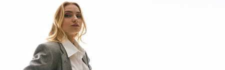 A young woman in chic attire exudes charisma while standing against a minimalist background.の写真素材