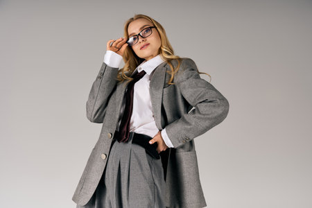 Confident young woman in trendy attire stands stylishly in a minimalist studio.の写真素材