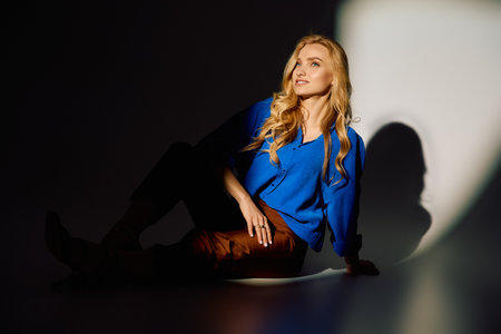 A beautiful young woman lounges in fashionable clothes, showcasing her chic style and confidence.の写真素材