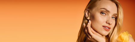 Young woman poses confidently, highlighting her trendy outfit against a warm orange backdrop.の写真素材