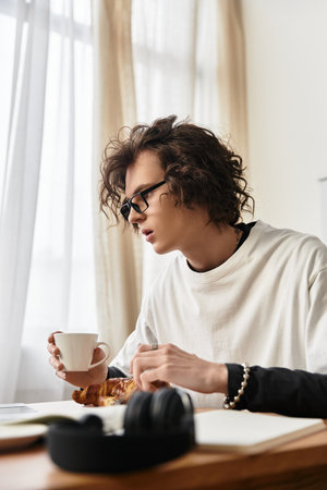 Cozy morning at home features a young man sipping coffee while savoring a pastry in comfort.