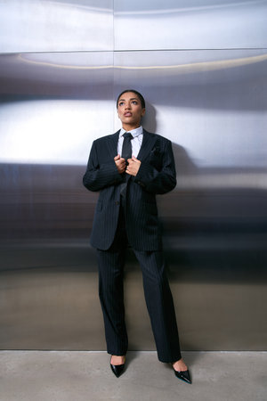 Stunning young woman showcases chic style in a tailored suit while posing gracefully indoors.の写真素材