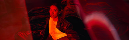 A stylish young woman poses confidently in trendy attire against an urban backdrop at night.の写真素材