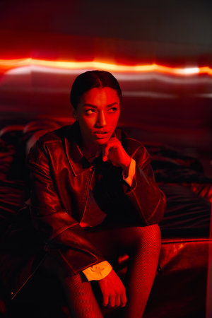 A young woman in stylish attire poses gracefully amid the lively nightlife.