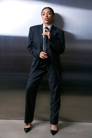 A young woman in fashionable attire strikes a confident pose in a stylish urban environment.の写真素材