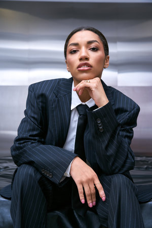 Stylish young woman confidently poses against a sleek backdrop.の写真素材