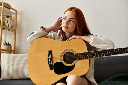 A young beautiful woman plays her guitar while relaxing on a comfortable sofa in a serene room.