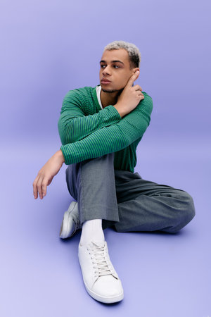 A fashionable young man with dyed hair showcases his unique style in a bright setting.