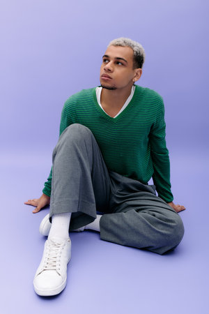A young man with dyed hair poses stylishly against a vibrant purple backdrop.