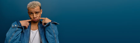 A young Black man shows off his style with dyed hair and a denim jacket, bannerの写真素材