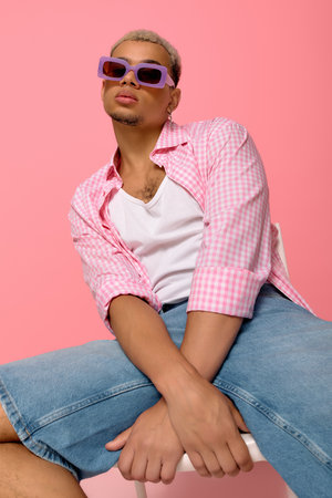 A young African American man poses stylishly in a checkered shirt and sunglasses.の写真素材