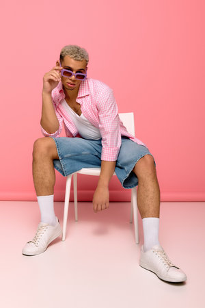 A stylish young man with dyed hair wears a checkered shirt and sunglasses, radiating confidence.の写真素材