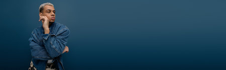 A young African American man showcases modern fashion with dyed hair in a denim jacket, bannerの写真素材