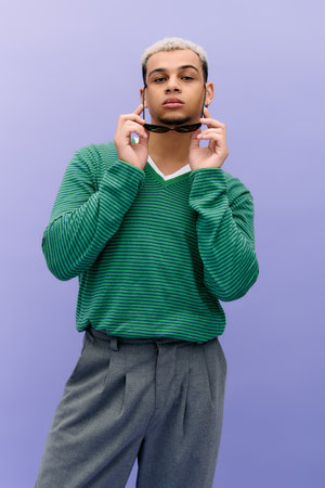 Confident young man with dyed hair poses in fashionable attire against a purple backdrop.
