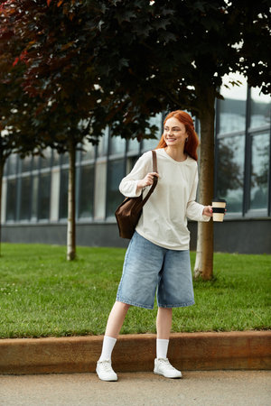 A young, beautiful woman stands in a lively urban park, smiling while holding coffee.