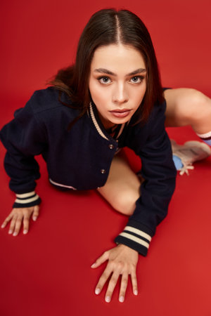 Young woman in trendy outfit poses playfully, exuding confidence against a vibrant backdrop.