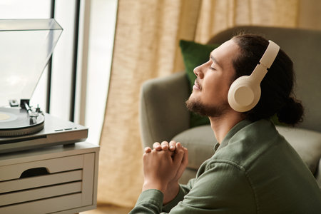 A young man at home, immersed in music, quietly enjoying peaceful moments with closed eyes.の写真素材