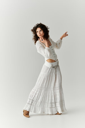 A beautiful woman in a flowing white outfit strikes an artistic pose, radiating elegance and style.の写真素材