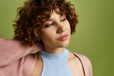 A young woman showcases her chic summer style with curly hair on a bright green background.