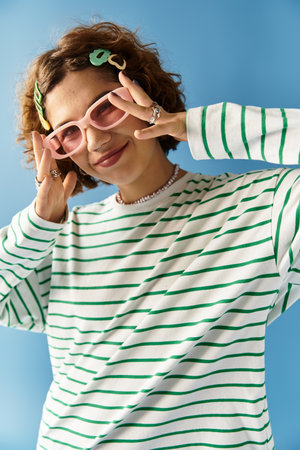 A joyful young woman with curly hair poses playfully in her colorful outfit and accessories.