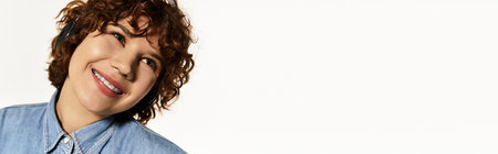 A young woman with short curly hair smiles warmly while dressed in a denim shirt, bannerの写真素材