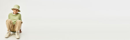 Happy boy in a colorful outfit sits on the floor, joyfully playing.の写真素材