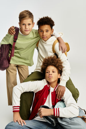 Three adorable boys in trendy outfits enjoy a fun moment, embracing friendship and togetherness.