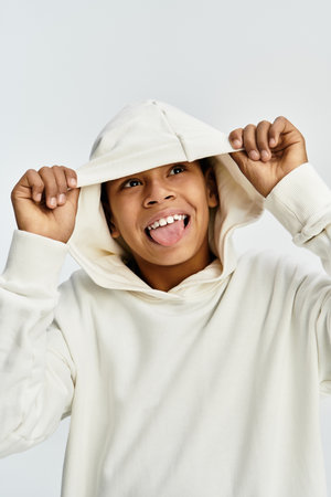 Joyful child in stylish attire expresses excitement while playfully adjusting his hoodie.の写真素材